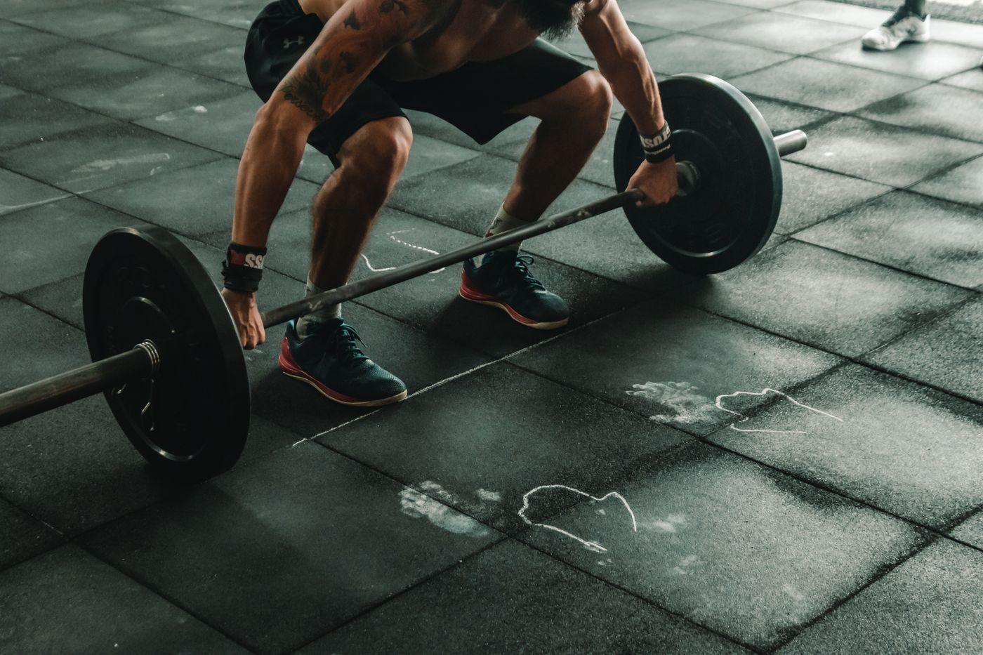Chalk dust on a training platform beside a loaded barbell