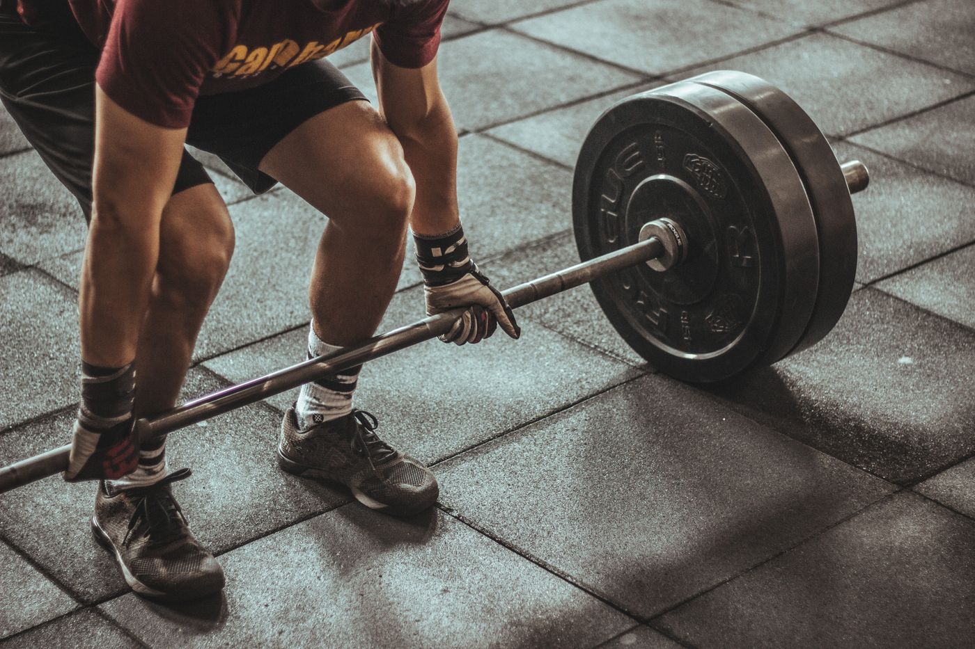 Member pulling a loaded barbell from the floor, chalk and dust in the air