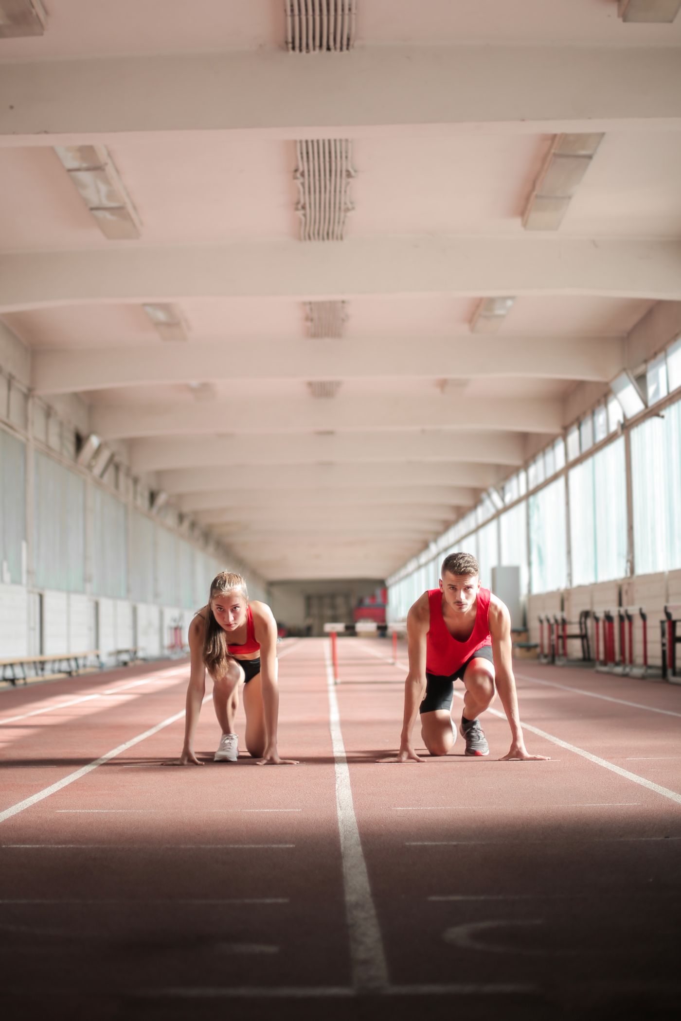 Two athletes set in the sprint start blocks on an indoor track